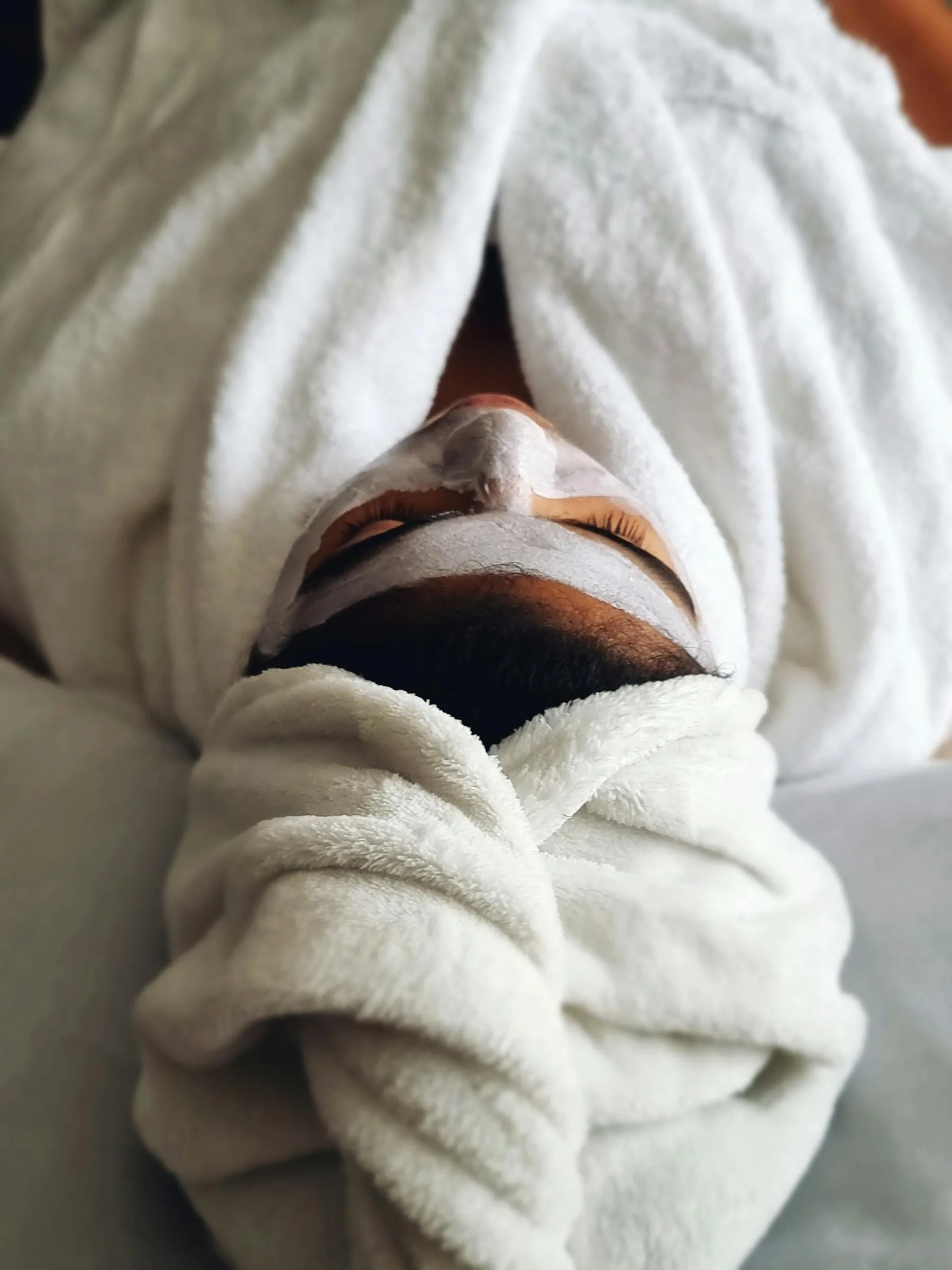 Woman relaxing during a professional facial treatment with a towel wrap